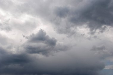 Sky threatening rain and sunshine passing through the clouds. Dark sky and black clouds before rainy, Dramatic black cloud and thunderstorm. The dark sky with heavy clouds converging and a violent storm before the rain.Bad or moody weather sky.
