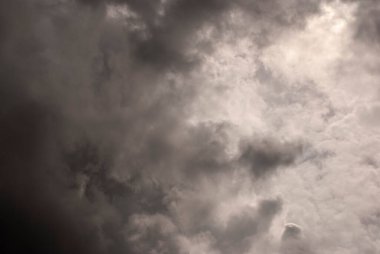 Sky threatening rain and sunshine passing through the clouds. Dark sky and black clouds before rainy, Dramatic black cloud and thunderstorm. The dark sky with heavy clouds converging and a violent storm before the rain.Bad or moody weather sky.