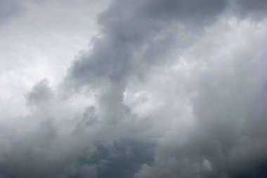 Sky threatening rain and sunshine passing through the clouds. Dark sky and black clouds before rainy, Dramatic black cloud and thunderstorm. The dark sky with heavy clouds converging and a violent storm before the rain.Bad or moody weather sky.