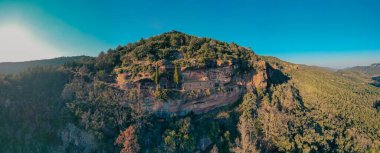 Uçuruma bakan bir kayanın altında gizlenmiş bir inziva yeri. Kızıl kayalıklarda yer alır ve yemyeşil ağaçlar ve ormanlarla çevrilidir.,