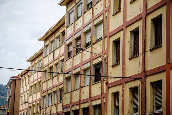 stock image The image showcases a multi-story residential building with a classic, rustic appearance characterized by alternating brick and white concrete walls. The structure is typical of an urban or suburban neighborhood, with multiple windows evenly spaced a