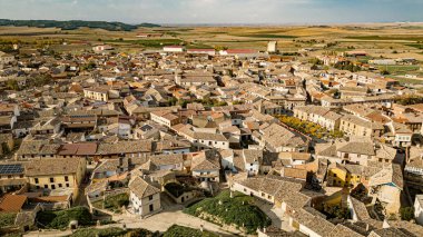 İspanya 'nın tarihi Astudillo kasabasının panoramik manzarasında ortaçağ La Mota Kalesi ve geleneksel yamaç şaraphaneleri sergilenmektedir. Kırsal çekiciliği ve mimari mirası yakalıyor..