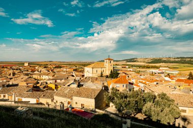 İspanya 'nın tarihi Astudillo kasabasının panoramik manzarasında ortaçağ La Mota Kalesi ve geleneksel yamaç şaraphaneleri sergilenmektedir. Kırsal çekiciliği ve mimari mirası yakalıyor..