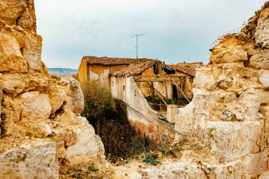 İspanya 'nın Castrojeriz kentindeki eski bir evin yıkıntıları kırsal mimari ve zamanın geçişini gösteriyor. Yakınındaki kilise ve kırsal manzaralı..