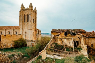 İspanya 'nın Castrojeriz kentindeki eski bir evin yıkıntıları kırsal mimari ve zamanın geçişini gösteriyor. Yakınındaki kilise ve kırsal manzaralı..