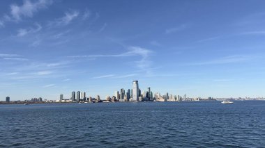 New York şehrinin ikonik gökdelenlerinin olduğu gökdelenlerin olduğu gökdelenlerin olduğu gökyüzü manzarası. Görüntü, Manhattan ve Jersey City 'nin güzelliğini ve ihtişamını sudan yansıtıyor. Şehir mimarisini ve kenti vurguluyor.