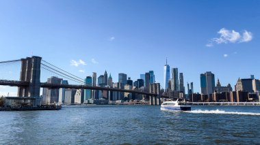Brooklyn Köprüsü ve New York Şehri, güneşli bir günde, şehrin güzelliğini sembolize eden East River 'ı geçen feribotla gökyüzüne yükseliyor..