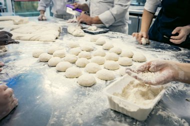 Profesyonel bir mutfakta taze parayla çalışan fırıncı öğrencilerin elleri. Bir aşçılık okulunda zanaatkar ekmek hazırlama, takım çalışması ve pasta eğitimi. Un, hamur topları ve yuvarlama teknikleri..