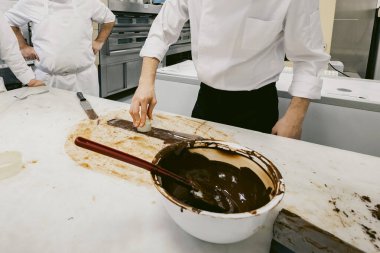 Profesyonel bir fırının mermer masasında erimiş çikolatayla çalışan bir pasta şefi. Çikolata soğutma süreci, gurme tatlı hazırlama ve şekerleme teknikleri..