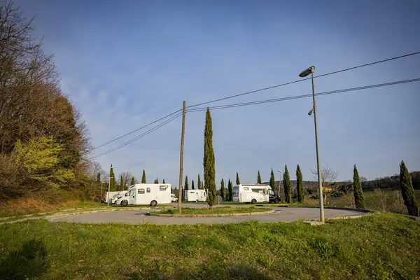 Güzel bir kırsal alanda çimenli bir arazide park etmiş beyaz bir karavan..