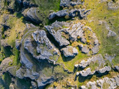 İnsansız hava aracı fotoğrafı soyut kaya oluşumlarını ve yukarıdan gelen yeşil araziyi gösteriyor. Jeolojik doku ve kalıplara sahip doğal manzara, tasarım ya da editoryal kullanım için mükemmel.