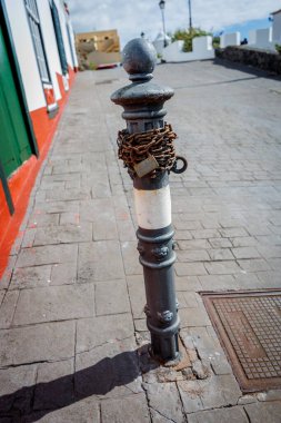 Aşınmış zincir ve asma kilide sarılı eski metal bir direğe yakın çekim, sınırlama, kontrol ve psikolojik kısıtlama hissi uyandırıyor..