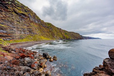 Okyanus manzaralı engebeli bir kıyı şeridi boyunca dramatik jeolojik oluşumlar, volkanik katmanlar, erozyon dokuları ve doğal detayları gösteriyor..