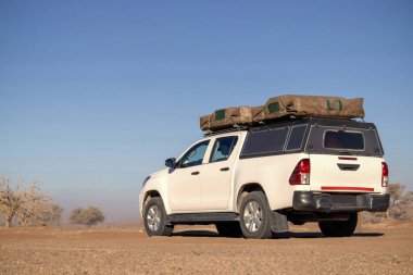 Güneşli bir günde Namib Çölü 'nün kırmızı kumlarında beyaz bir off-road arabası duruyor. Sossusvlei, Namibya