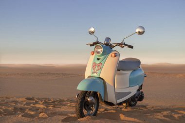 Namib Çölü 'nün altın kumda gün batımında geriye dönük mavi scooter.
