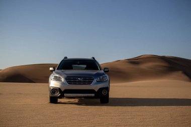 Gray Subaru in the sand of the Namib desert at a bright sky. Walvis Bay, Namibia.