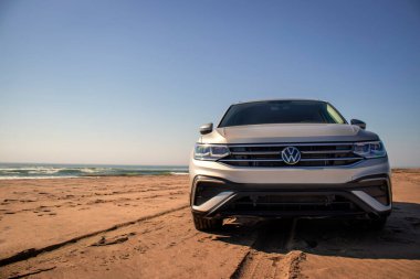 Gri Volkswagen Tiguan Namib Çölü 'nün kıyı şeridinde parlak bir gökyüzünde. Walvis Körfezi, Namibya. 
