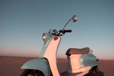 Namib Çölü 'nün altın kumda gün batımında geriye dönük mavi scooter.