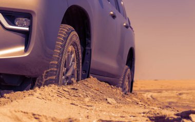 Namib çölünde kumda sıkışmış altın bir arabanın yakınında..