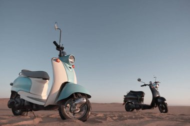 Namib Çölü 'nün altın kumlarında gün batımında iki tane Retro scooter.