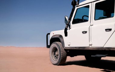 Güneşli bir günde Namib Çölü 'nün kumlarında duran bir arabanın yakın çekimi.. 