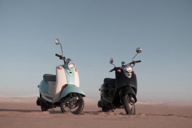 Namib Çölü 'nün altın kumlarında gün batımında iki tane Retro scooter.