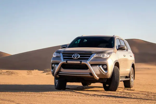 stock image A gray Toyota Fortuner in the middle of the Namib Desert against a bright sky