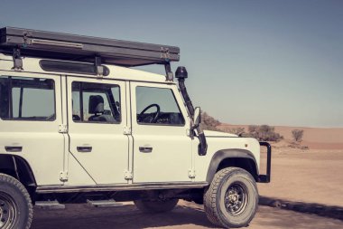 Güneşli bir günde çölün ortasında beyaz bir off-road arabası.