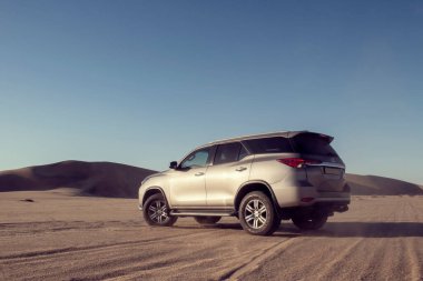 Gri Toyota Fortuner Namib Çölü 'nün kumlarında parlak gökyüzünde. Walvis Körfezi, Namibya.