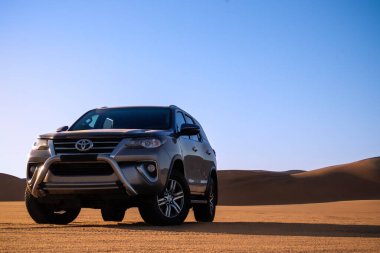 Gri Toyota Fortuner Namib Çölü 'nün kumlarında parlak gökyüzünde. Walvis Körfezi, Namibya.