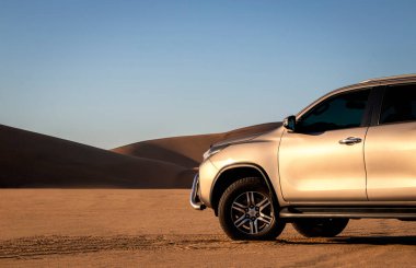 Namib Çölü 'nün ortasında parlak bir gökyüzüne karşı gri bir Toyota Fortuner.