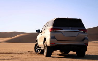 Namib Çölü 'nün ortasında parlak bir gökyüzüne karşı gri bir Toyota Fortuner.