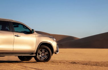 Namib Çölü 'nün ortasında parlak bir gökyüzüne karşı gri bir Toyota Fortuner.