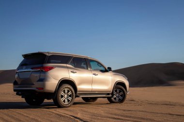 Namib Çölü 'nün ortasında parlak bir gökyüzüne karşı gri bir Toyota Fortuner.