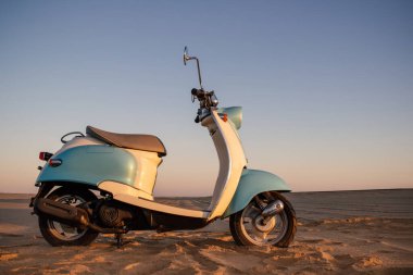 Namib Çölü 'nün altın kumda gün batımında geriye dönük mavi scooter.