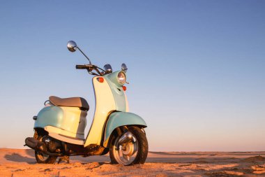 Namib Çölü 'nün altın kumda gün batımında geriye dönük mavi scooter.