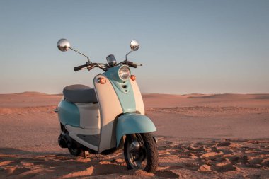 Namib Çölü 'nün altın kumda gün batımında geriye dönük mavi scooter.