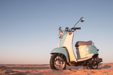 Namib Çölü 'nün altın kumda gün batımında geriye dönük mavi scooter.