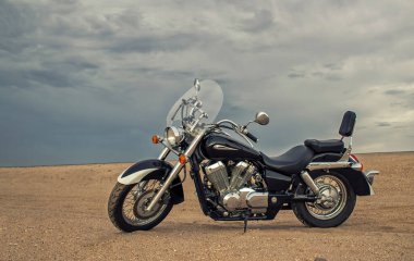 Çölde park etmiş off-road motosikleti dramatik bulutlu gökyüzü macerası seyahat, özgürlük ve aşırı doğa manzarası konsepti altında