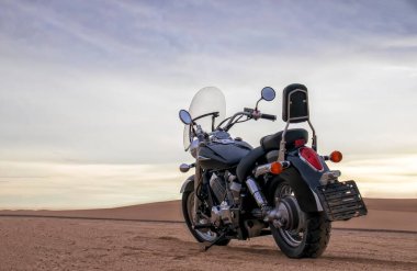 Çölde park etmiş off-road motosikleti dramatik bulutlu gökyüzü macerası seyahat, özgürlük ve aşırı doğa manzarası konsepti altında