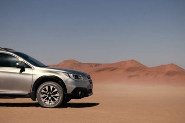 Güneşli bir günde Namib Çölü 'nün altın kumlarında gri bir araba duruyor. 29.08.2021. Sossusvlei, Namibya