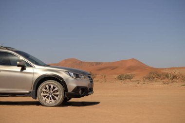 Gri Subaru, Namib çölünün kumlarında, parlak bir gökyüzünde.