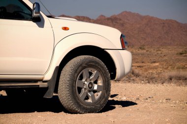Güneşli bir günde Namib Çölü 'nün kırmızı kumlarında beyaz bir off-road arabası duruyor. Sossusvlei, Namibya