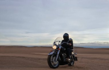 Gün batımında motosikletli bir adamın gerçek fotoğrafı dramatik bulutlar içinde özgürlük, seyahat, yalnızlık, macera ve açık arazide açık hava yaşam tarzı kavramı.