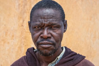 Derin kırışıklıkları ve anlamlı gözleri olan yaşlı bir Afrikalı adamın portresi. İnsan gücünü, bilgeliğini ve zamansızlığını yansıtan doğal ve duygusal bir görüntü.