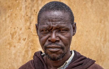 Derin kırışıklıkları ve anlamlı gözleri olan yaşlı bir Afrikalı adamın portresi. İnsan gücünü, bilgeliğini ve zamansızlığını yansıtan doğal ve duygusal bir görüntü.