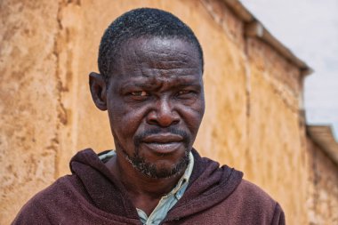 Derin kırışıklıkları ve anlamlı gözleri olan yaşlı bir Afrikalı adamın portresi. İnsan gücünü, bilgeliğini ve zamansızlığını yansıtan doğal ve duygusal bir görüntü.