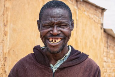 Derin kırışıklıkları ve anlamlı gözleri olan yaşlı bir Afrikalı adamın portresi. İnsan gücünü, bilgeliğini ve zamansızlığını yansıtan doğal ve duygusal bir görüntü.