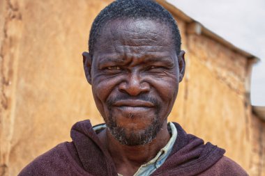 Derin kırışıklıkları ve anlamlı gözleri olan yaşlı bir Afrikalı adamın portresi. İnsan gücünü, bilgeliğini ve zamansızlığını yansıtan doğal ve duygusal bir görüntü.