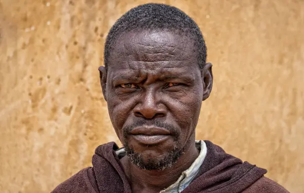 Derin kırışıklıkları ve anlamlı gözleri olan yaşlı bir Afrikalı adamın portresi. İnsan gücünü, bilgeliğini ve zamansızlığını yansıtan doğal ve duygusal bir görüntü.